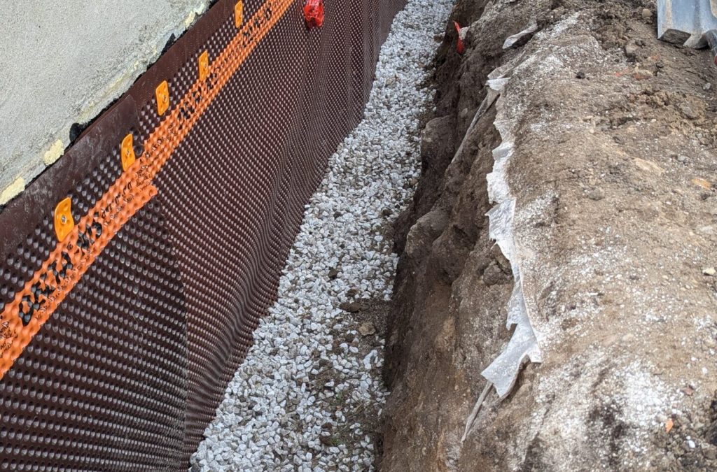 exterior basement waterproofing in point edward with membrane on foundation and gravel at bottom of trench